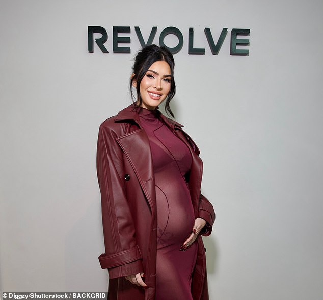 The burgundy dress was paired with sky-high black heels and a matching leather coat, with the star cradling her baby bump on the red carpet.