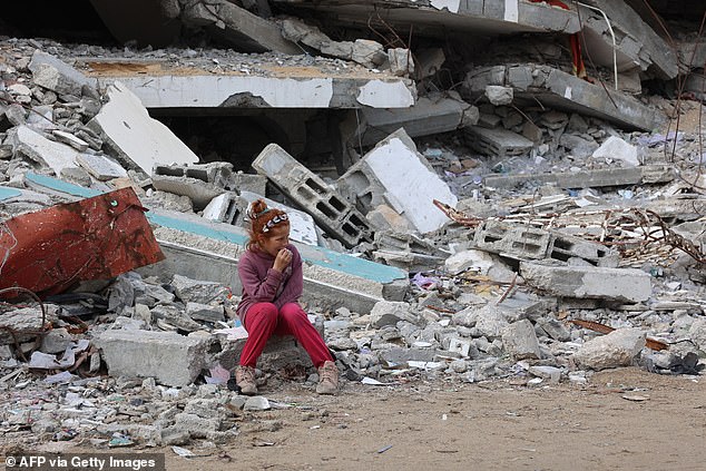 A Palestinian girl rests on the rubble of a destroyed building west of Gaza City, November 25, 2024.