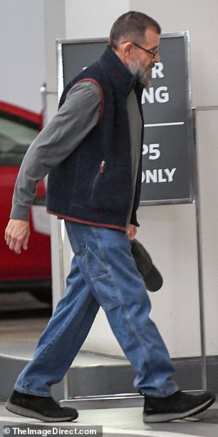 He also wore a gray long-sleeved shirt, a black LL Bean vest, bootcut jeans and black loafers.