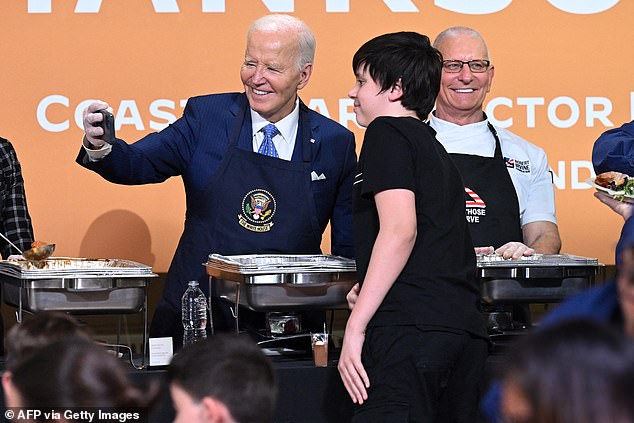 President Joe Biden takes a selfie while working a food line during a 'Friendsgiving' dinner for Coast Guard families on Staten Island Monday evening