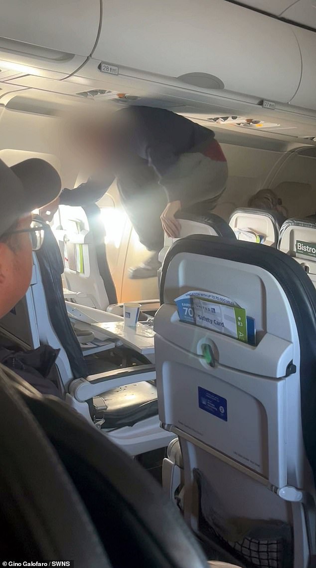 The individual can be seen holding an aisle and exit row seat while kicking the chair in the middle with enough force to knock it into the back row.