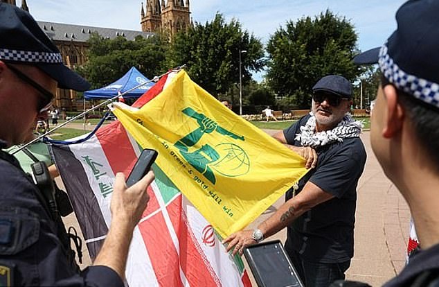 Al Yazbek was also photographed holding a yellow flag similar to the Hezbollah flag but with Ned Kelly at the protest in Hyde Park.