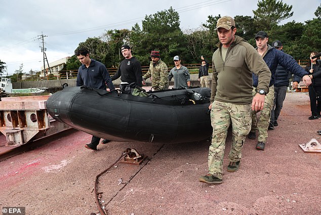 Pictured: A search team scouring the scene after an Osprey crash in Japan that killed eight service members, including one from Massachusetts, in November 2023