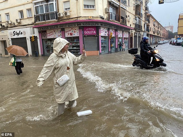 A woman takes a photograph of a flooded street in Malaga, Andalusia, Spain, November 13, 2024