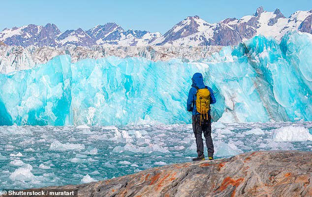 A hiker looks at a huge glacier near Kulusuk, Greenland