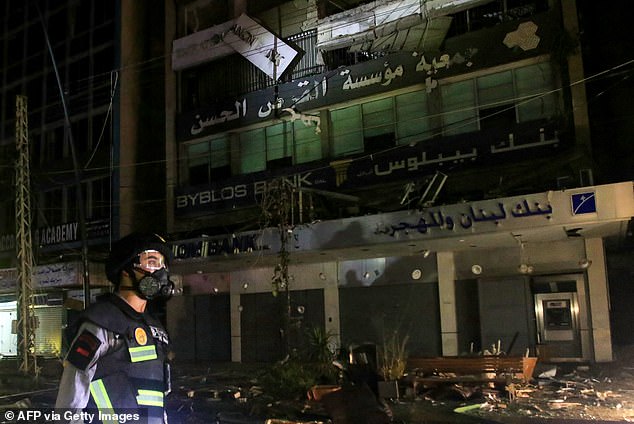 A member of the Lebanese emergency services walks at the scene of an Israeli airstrike that targeted a building reportedly housing a Hezbollah-backed financial institution in the southern Lebanese city of Sidon.