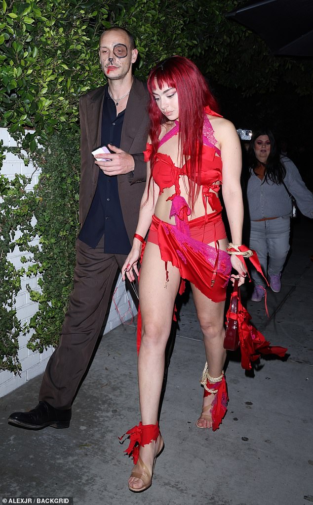 She paired it with a pair of strappy heels, with ropes tied around her ankles, and a dark red wig.