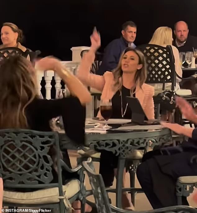 The two women, who remain strangers, are seen raising their hands in joy as Trump, wearing his trademark red MAGA hat, raises a fist and applauds.