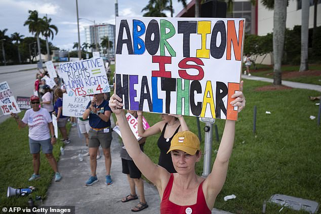 People hold signs during a rally for abortion rights on the second anniversary of the Supreme Court ruling to overturn Roe v. Wade, in West Palm Beach, Florida, on June 24, 2024.