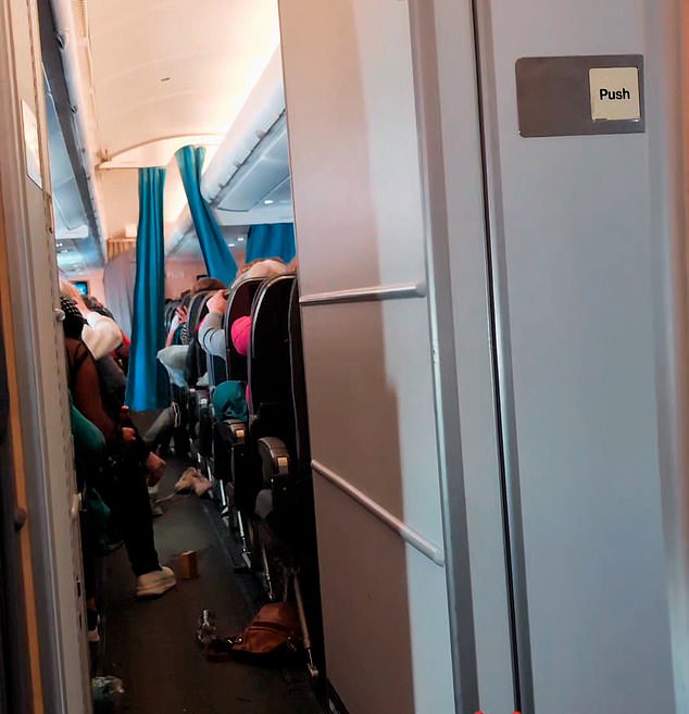 Passengers are seen clinging to the backs of their seats as the plane was rocked by extreme turbulence.