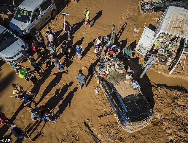 Volunteers and neighbors clean the mud four days after flash floods devastated everything in their path in Paiporta, on the outskirts of Valencia.