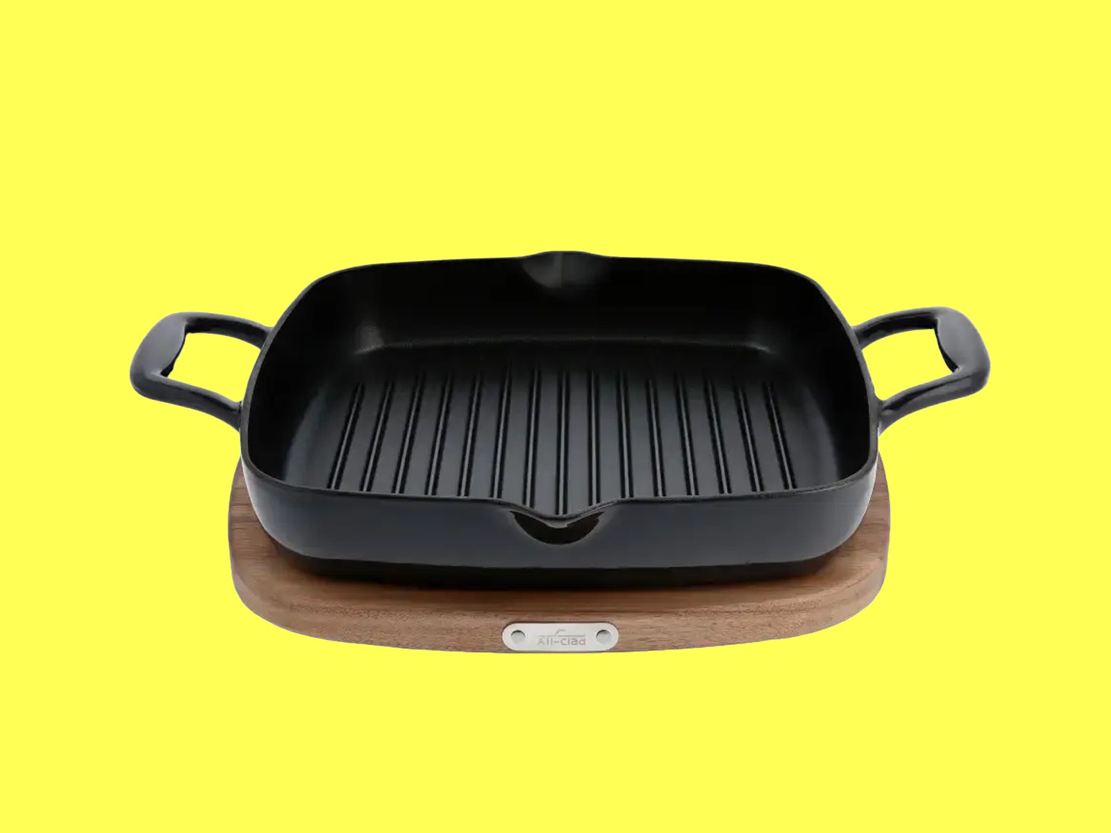 AllClad grill with handle on each side on a wooden disc