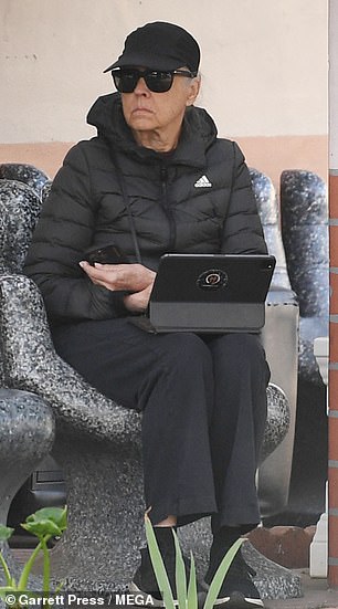 He sat on a bench using his tablet while he waited for his BMW.