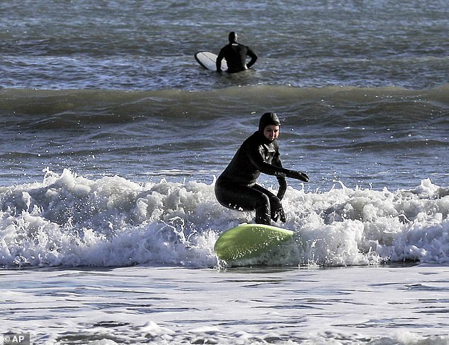 Tulsi Gabbard, then a Democratic presidential primary candidate, is seen surfing on New Year's Day 2020 off the coast of New Hampshire in a winter wetsuit.