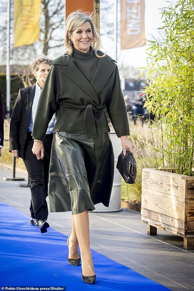 Her dark green outfit included an A-line skirt, a turtleneck, and a belted wool jacket.