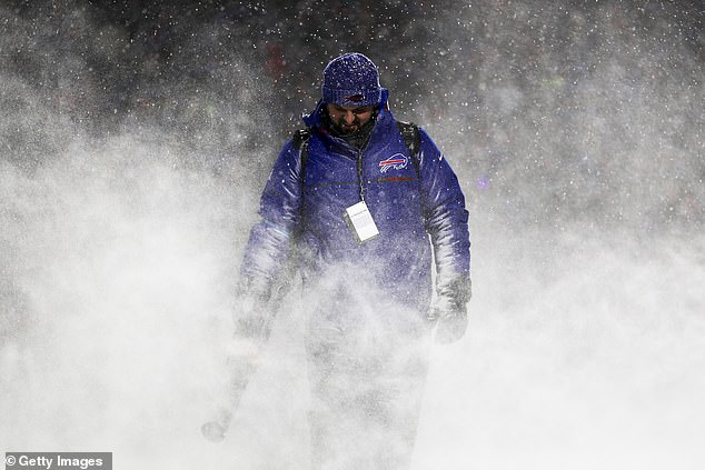 A grounds crew member blows snow off the field during a timeout on Sunday Night Football