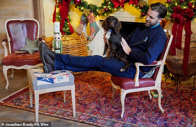 Dog trainer Sean Welland with spaniel Elspeth rests his leg on a stool with a cushion created from recycled curtains, in Highgrove