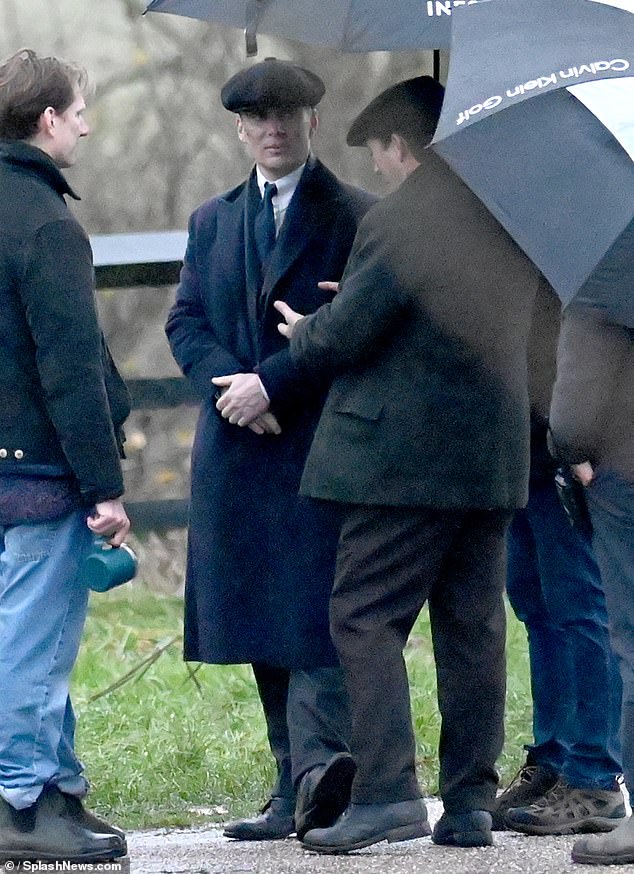 Murphy and Lee sheltered under umbrellas between takes as it began to rain in northeast Wales on Sunday.