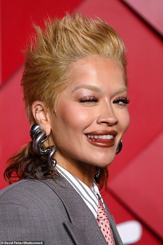 Rita elevated her tailored suit by pairing it with a series of extravagant metallic jewelry, including huge silver spiral earrings.