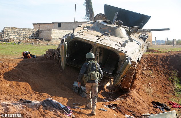 A rebel fighter walks near a military vehicle in Menagh, north of Aleppo, Syria, on December 2