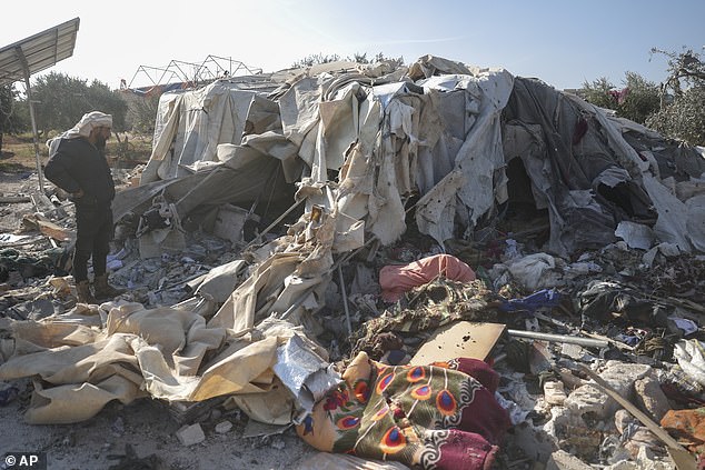 A man looks at an internally displaced persons camp destroyed in an airstrike near the village of Harbnush