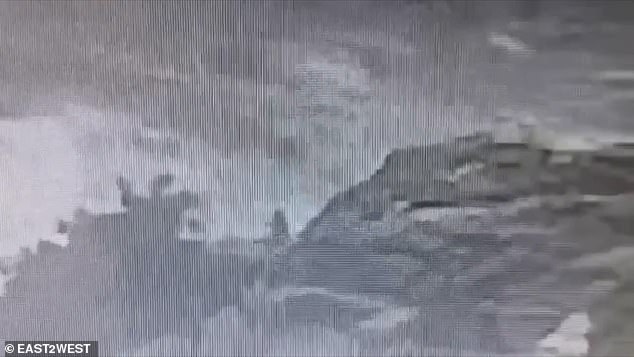 The clip shows Kamilla from behind as she sits on the rock and wave after wave rushes towards her.