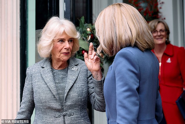 Queen Camilla crosses her fingers as she bids farewell to France's first lady, Brigitte Macron, after the book prize ceremony today in London.