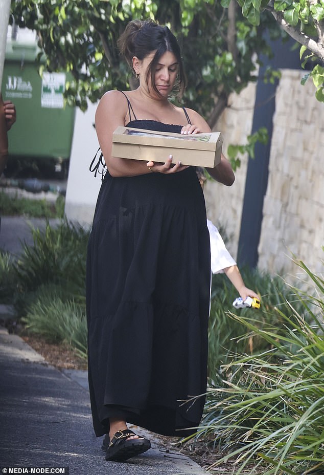 Meanwhile, John's very pregnant wife Jessie was wearing a black maternity dress and showing off her growing baby bump as she carefully carried some smaller boxes to their property.