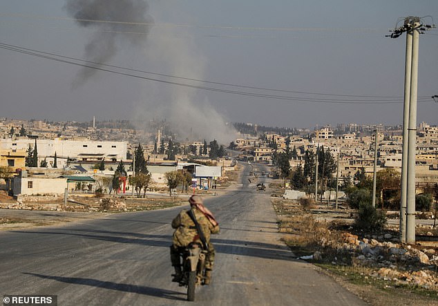 Smoke rises as a member of the rebels led by the Islamist militant group Hayat Tahrir al-Sham rides a motorcycle in al-Rashideen, Aleppo province, Syria, on November 29, 2024.