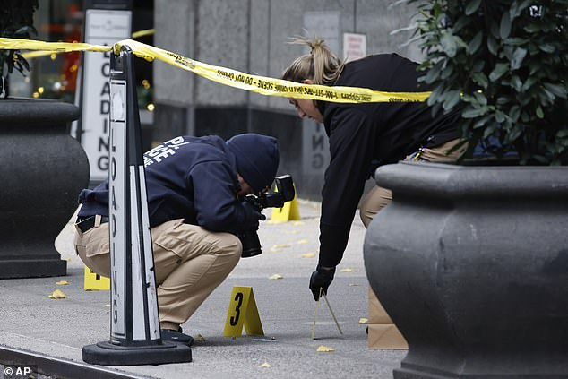 Members of the New York Police Department's Crime Scene Unit photograph bullets littering the sidewalk as they investigate the scene outside the Hilton Hotel