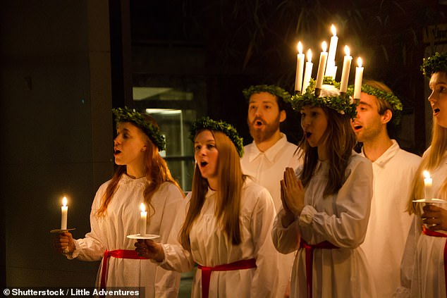 Choristers wear candles in their hair for the celebration of Lucía in Sweden