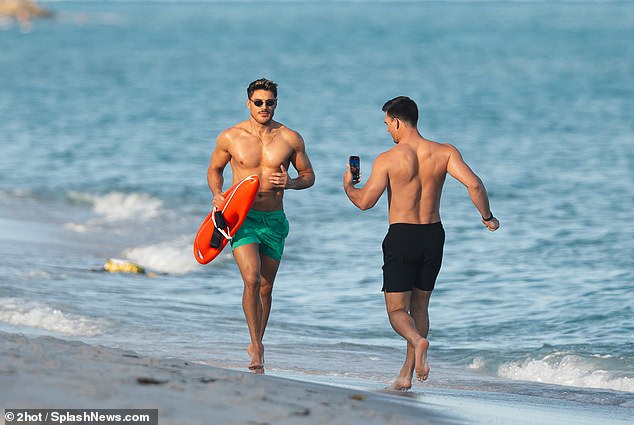 The TV personality later filmed the stylist as he ran along the shore while holding an orange paddleboard in his hand.