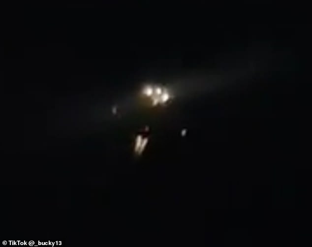 One of the UFO drones, whose engines can be heard roaring from the ground, appeared to have a cluster of white lights on its underbelly, while red lights flashed on its wingtips and tail (above)