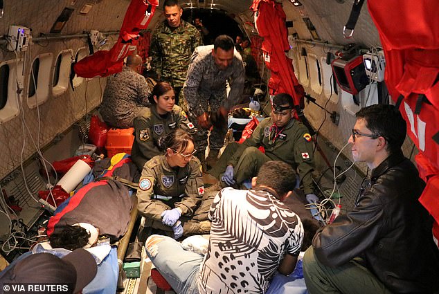 Colombian Air Force soldiers and staff from the Colombian Family Welfare Institute (ICBF) provide medical assistance on an airplane to the surviving children of a Cessna 206 plane crash