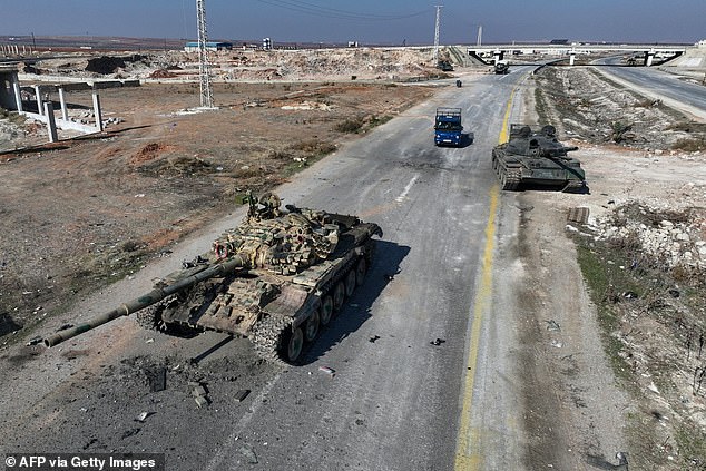 An aerial image shows a car passing by Syrian army military equipment and vehicles that were abandoned on the road to Damascus, near the city of Suran, on December 3, 2024.