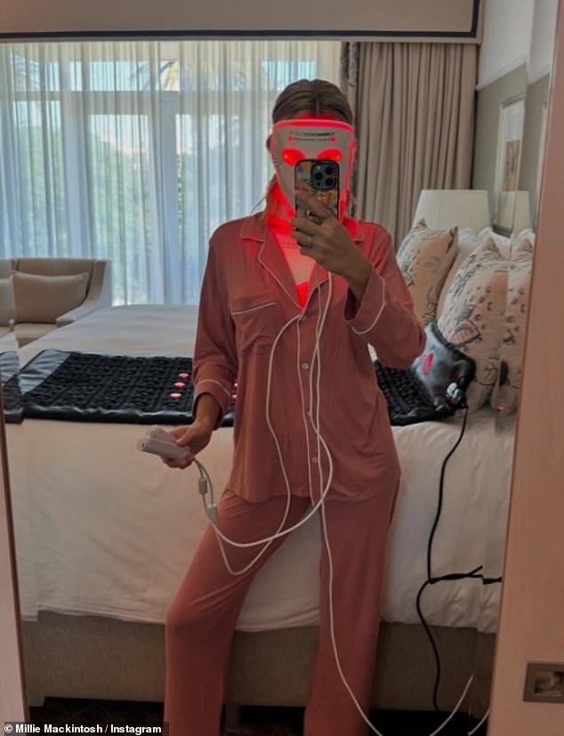 Millie took a selfie while applying an LED light therapy facial mask in her pajamas