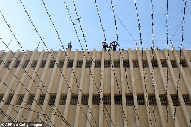 People stand on the roof of Saydnaya prison as Syrian rescuers search for hidden basements.