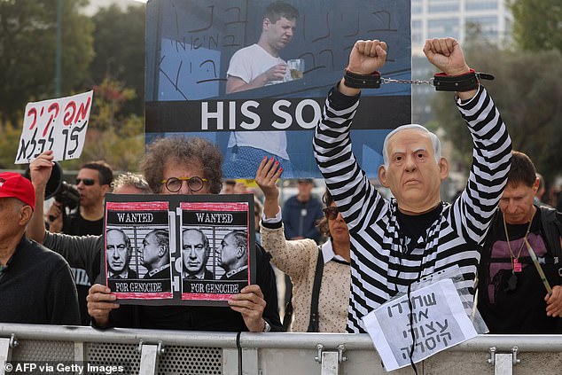 Protesters chant slogans and hold banners at a demonstration against Benjamin Netanyahu during his trial on corruption charges at the Tel Aviv District Court.