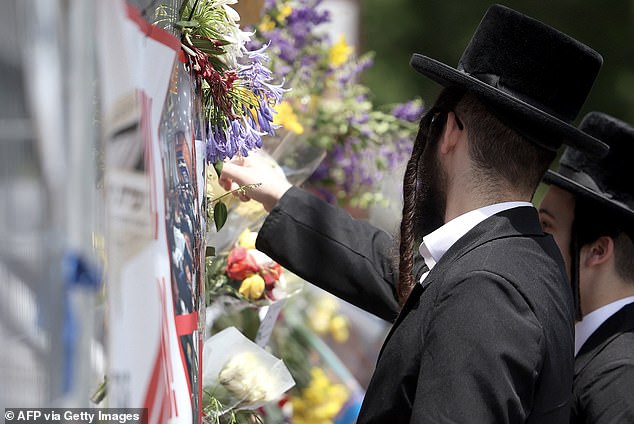 Members of the Jewish community are seen reading messages outside the synagogue.