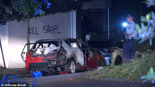 Anti-Semitic graffiti was painted on a wall behind a burnt-out car in Woollahra.