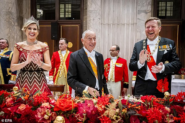 Máxima, who paired her stunning ensemble with a shawl, smiled as she and her husband were photographed toasting Mr. de Sousa at the table.