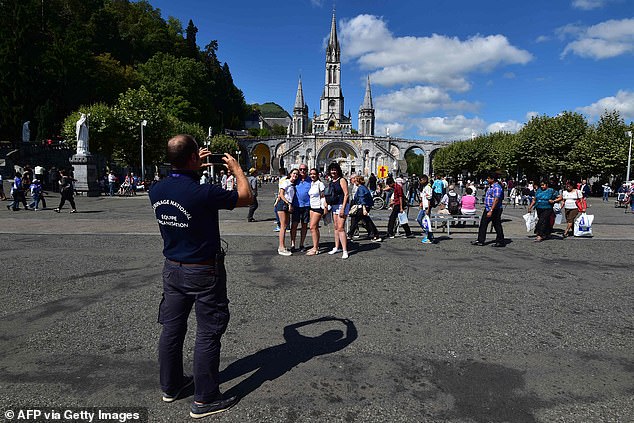 In this file photo taken on August 15, 2018, Catholic pilgrims pose in front of the Basilica of Our Lady of the Rosary during the celebration of the Feast of the Assumption, in the pilgrimage city of Lourdes, southwestern France.