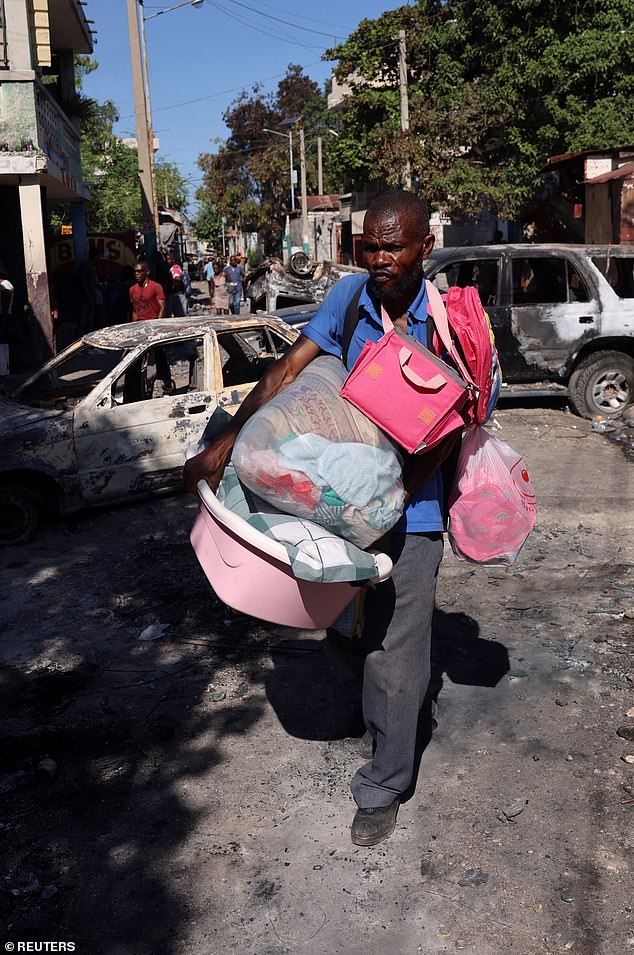 A man carries his belongings as he flees home after last weekend's violence by armed gangs, many of whom have grouped behind an alliance known as Viv Ansanm in Poste Marchand, a suburb of Port-au-Prince, the capital of Haiti.