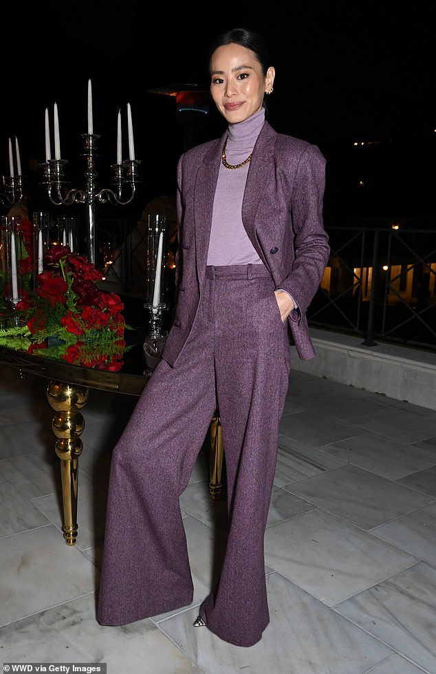 She paired the suit with a high-necked lilac blouse and gold chain necklace, as well as jeweled striped stilettos.