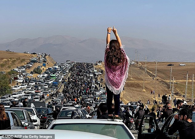 The 2022 protests in Iran showing an unveiled woman standing on top of a car. Amnesty International has criticized new laws that say women could be sentenced to death for sending videos of themselves unveiled to media outlets outside the Islamic Republic.