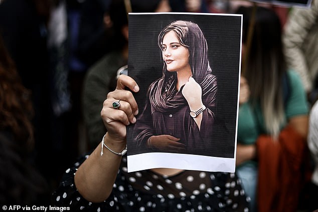 A protester holds a portrait of Mahsa Amini during a demonstration in Brussels. The law comes two years after protests rocked Iran following the death in custody of 22-year-old Mahsa Amini.