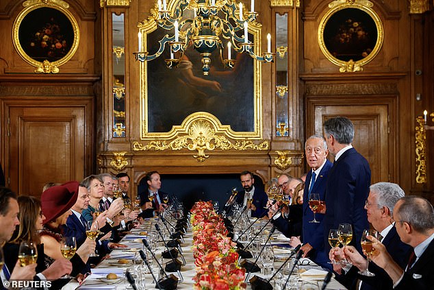 Before sitting at the long table, Máxima took off her coat to reveal a dress with a paisley print and wine-colored feathers covering her neckline.