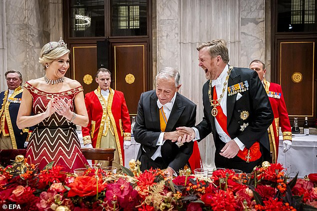 The Dutch king is seen unable to contain his laughter as he shakes hands with Mr de Sousa after giving a speech at the banquet.