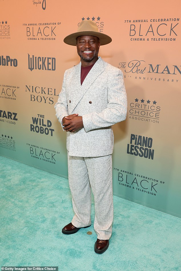 Taye was dressed to the nines in a loose-fitting gray double-breasted suit over black leather dress shoes and a huge brown hat.