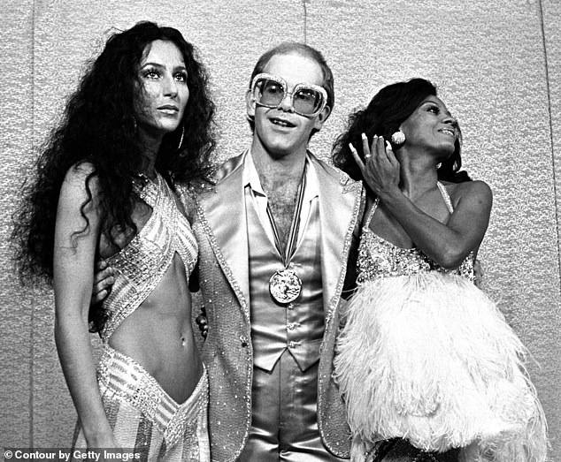 The 'Benny and the Jets' singer (center)'s own history of substance abuse and his experiences with others have shaped his perspective on legal marijuana. He is pictured with Cher and Diana Ross in 1975, about a year after John was introduced to cocaine.